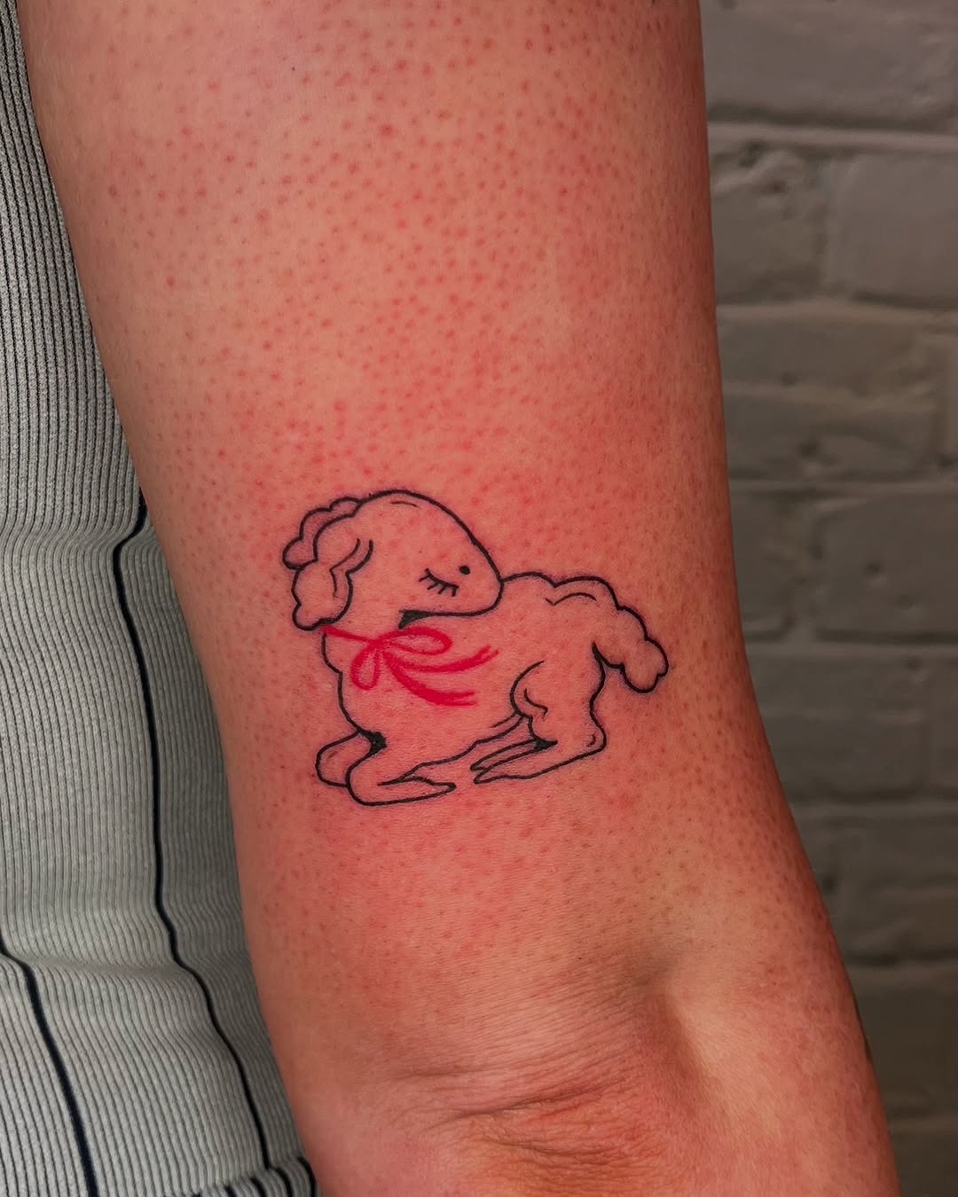 Playful lamb tattoo with a charming red ribbon Tattoo Design