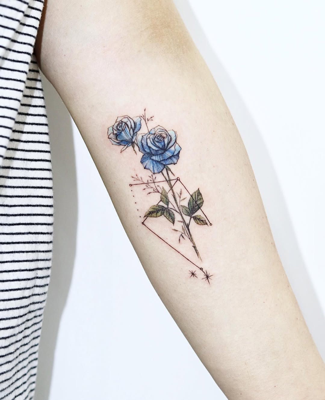 This tattoo showcases two stunning blue roses, beautifully intertwined with delicate starry details.