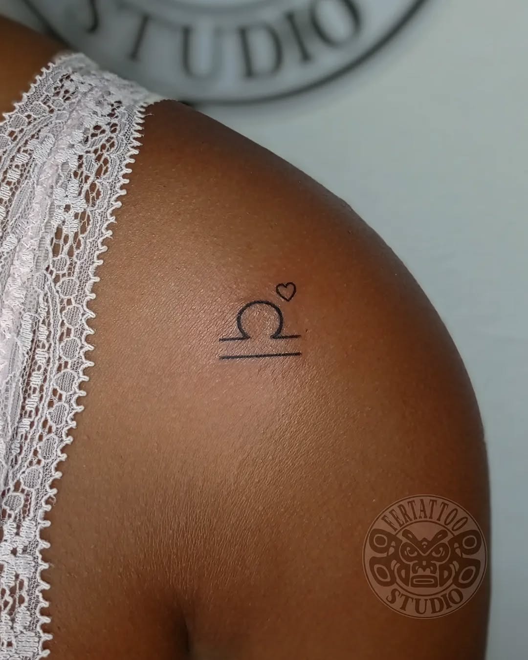 This minimalist tattoo features the Libra zodiac symbol, subtly adorned with a delicate heart.