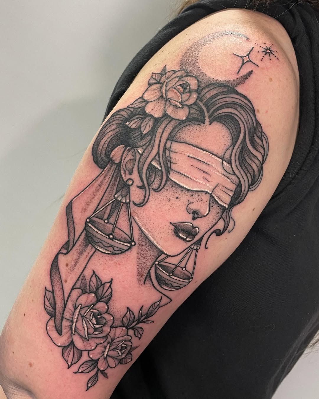 This striking tattoo features a blindfolded woman adorned with roses and Libra scales, representing balance and mystery.