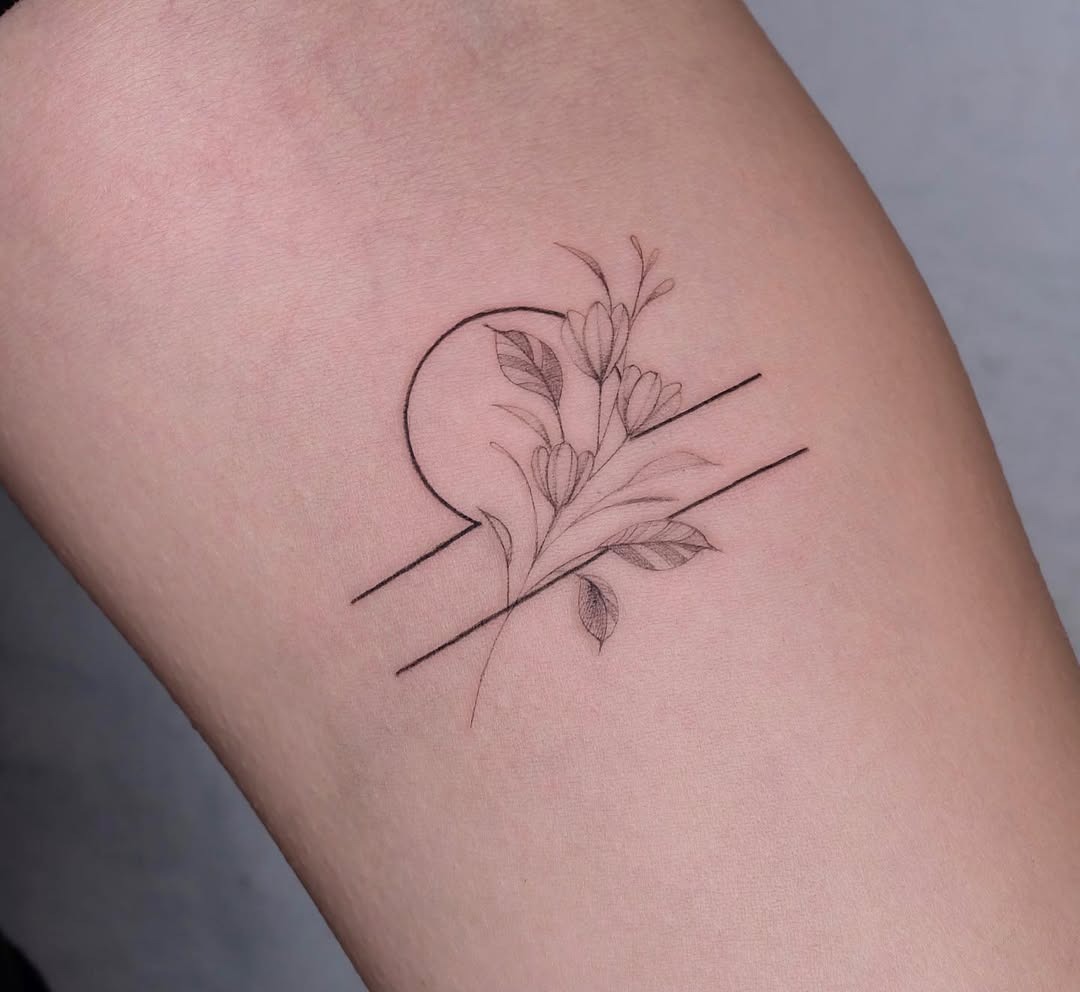 This tattoo features a minimalist design showing a Libra symbol intertwined with delicate flowers.