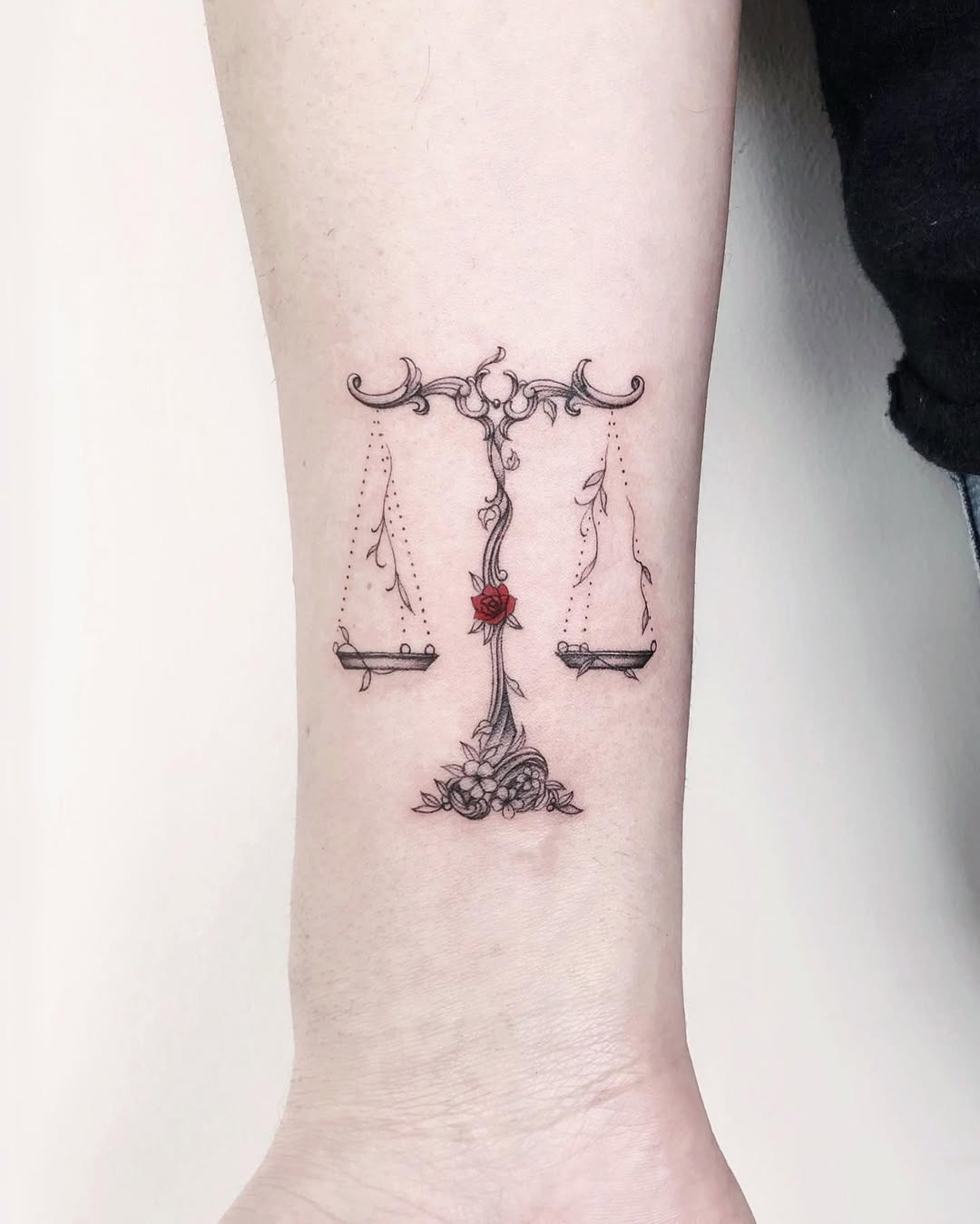 This tattoo beautifully depicts Libra's scales, adorned with delicate roses.