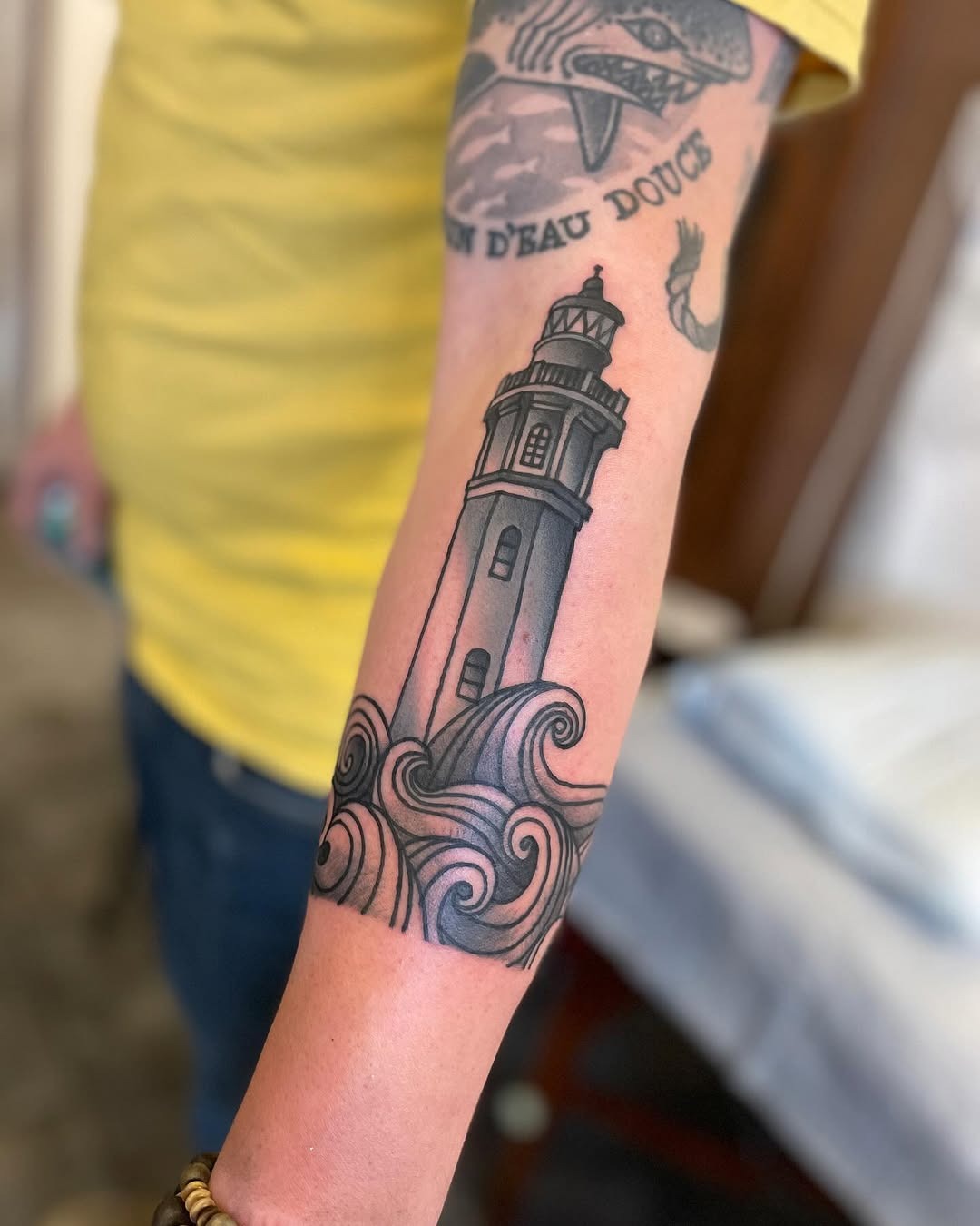 Stylized lighthouse amidst swirling ocean waves Tattoo Design