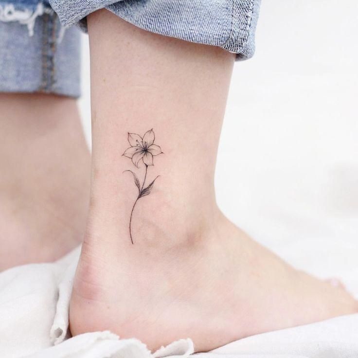 A perfect example of a small and dainty tattoo, this ankle tattoo features a tiny lily drawn with thin lines and minimal shading.
