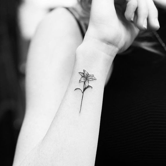 This wrist tattoo showcases a tiny lily drawn with clean lines and minimal details.