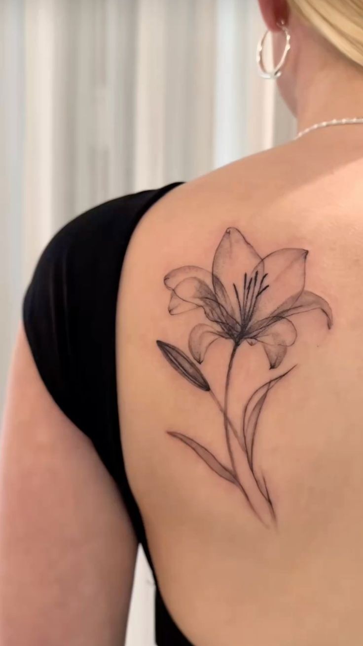 Graceful Lily Silhouette Tattoo, a tattoo design rendered in delicate fine-line for the shoulder.