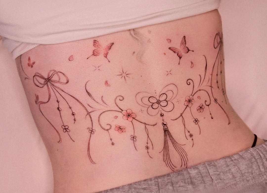 This lower back tattoo features graceful floral elements and playful butterflies.