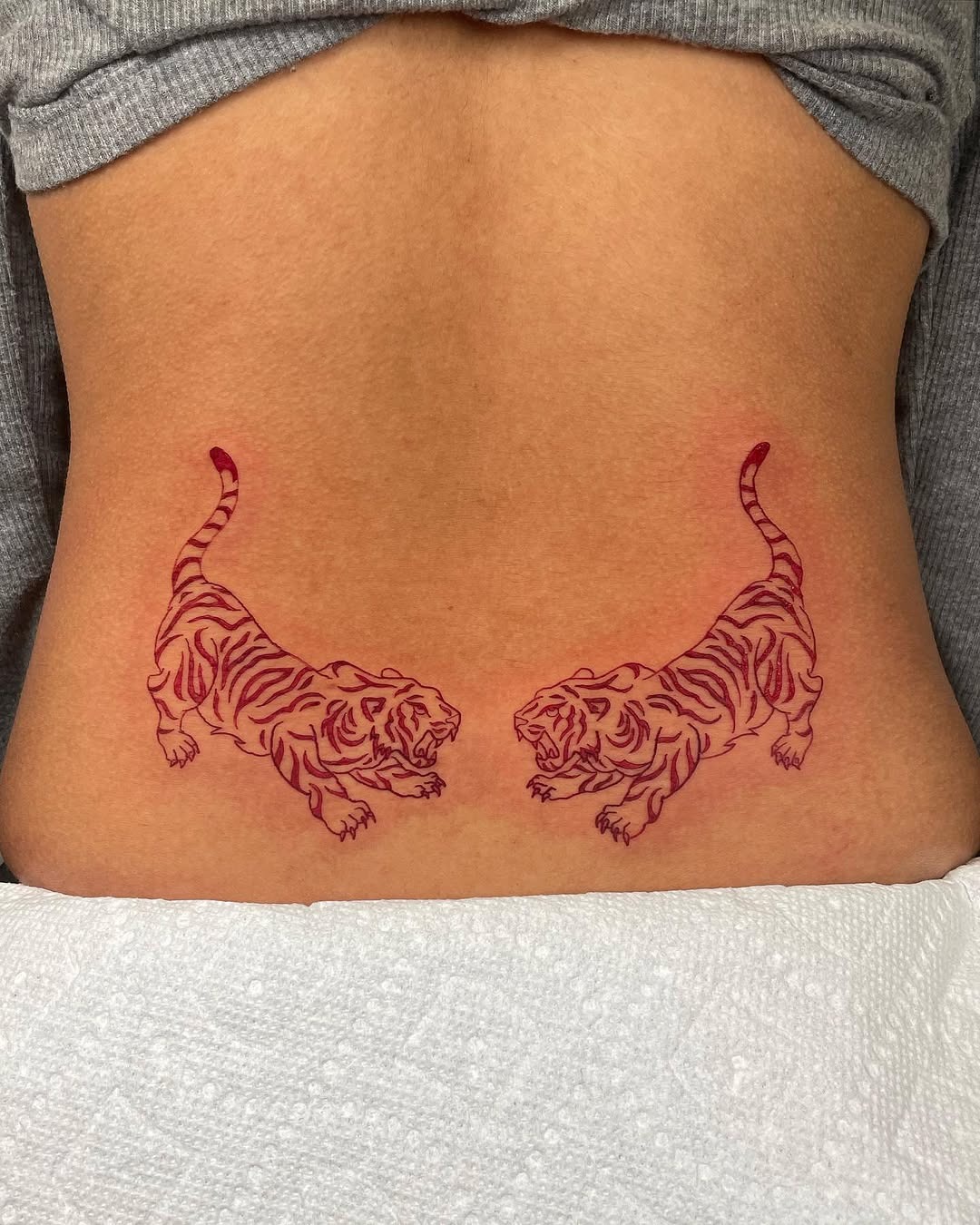 This striking tattoo features two fierce tigers in a bold, red hue.