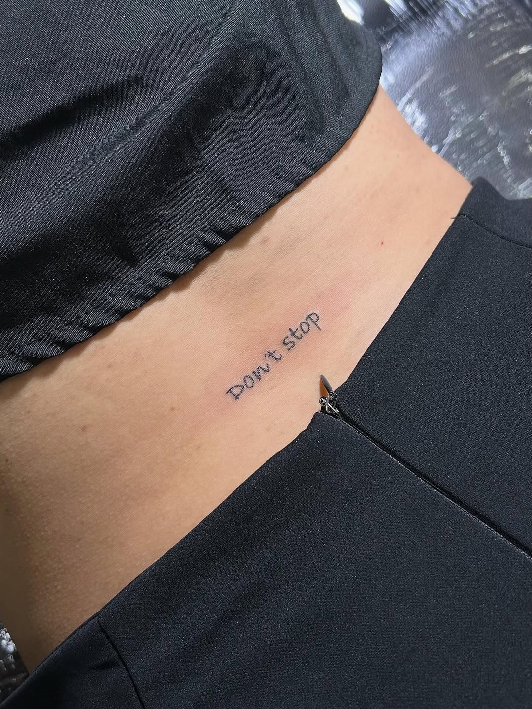 This lower back tattoo features the phrase 'Don't stop' in a simple, understated font.