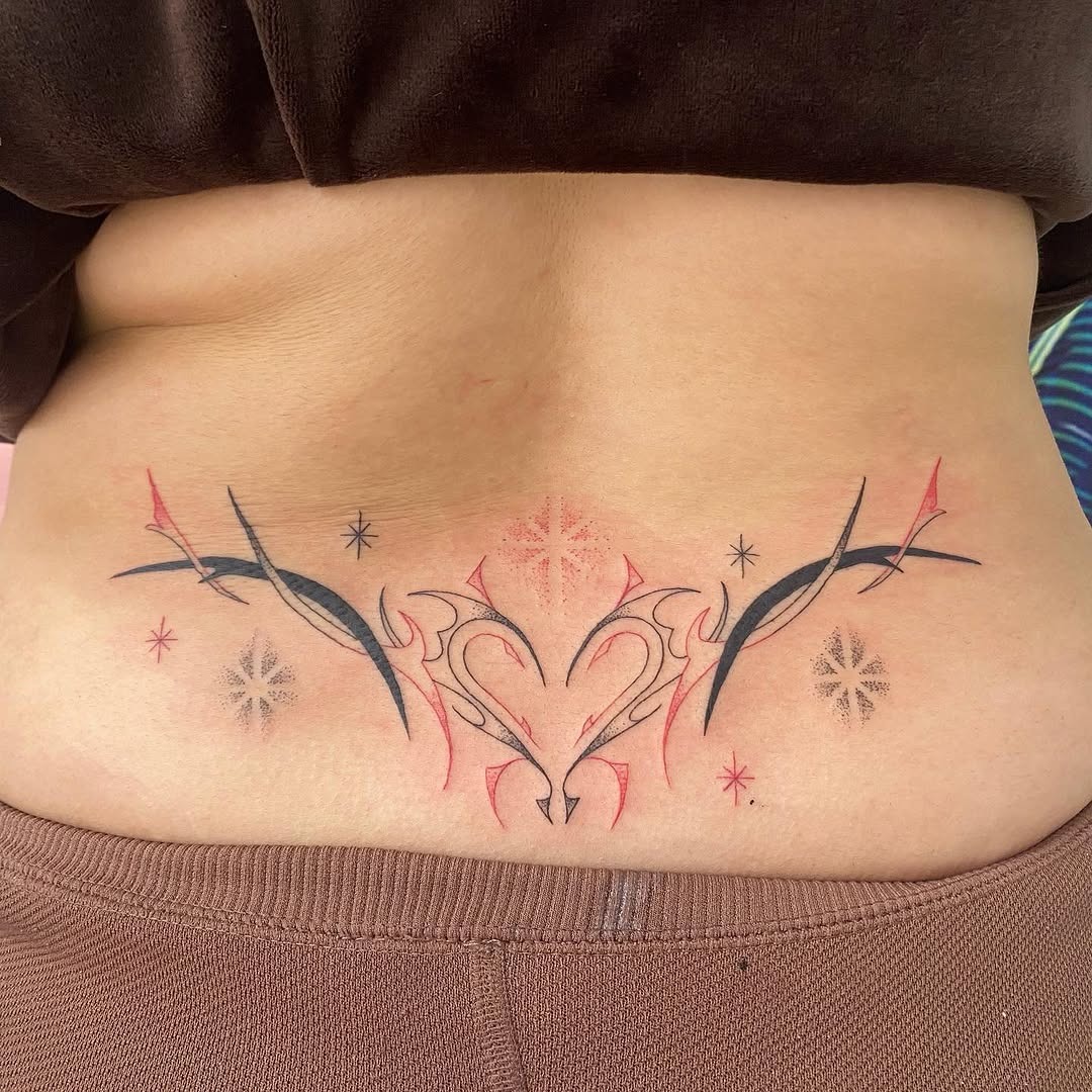 This lower back tattoo showcases a unique tribal design intertwined with a heart shape.