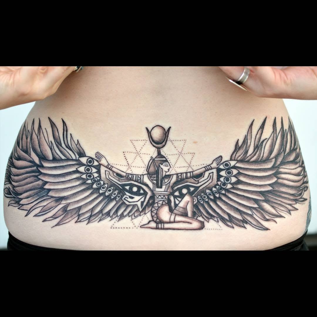 This captivating lower back tattoo features an elegant design of expansive wings paired with mystical elements.