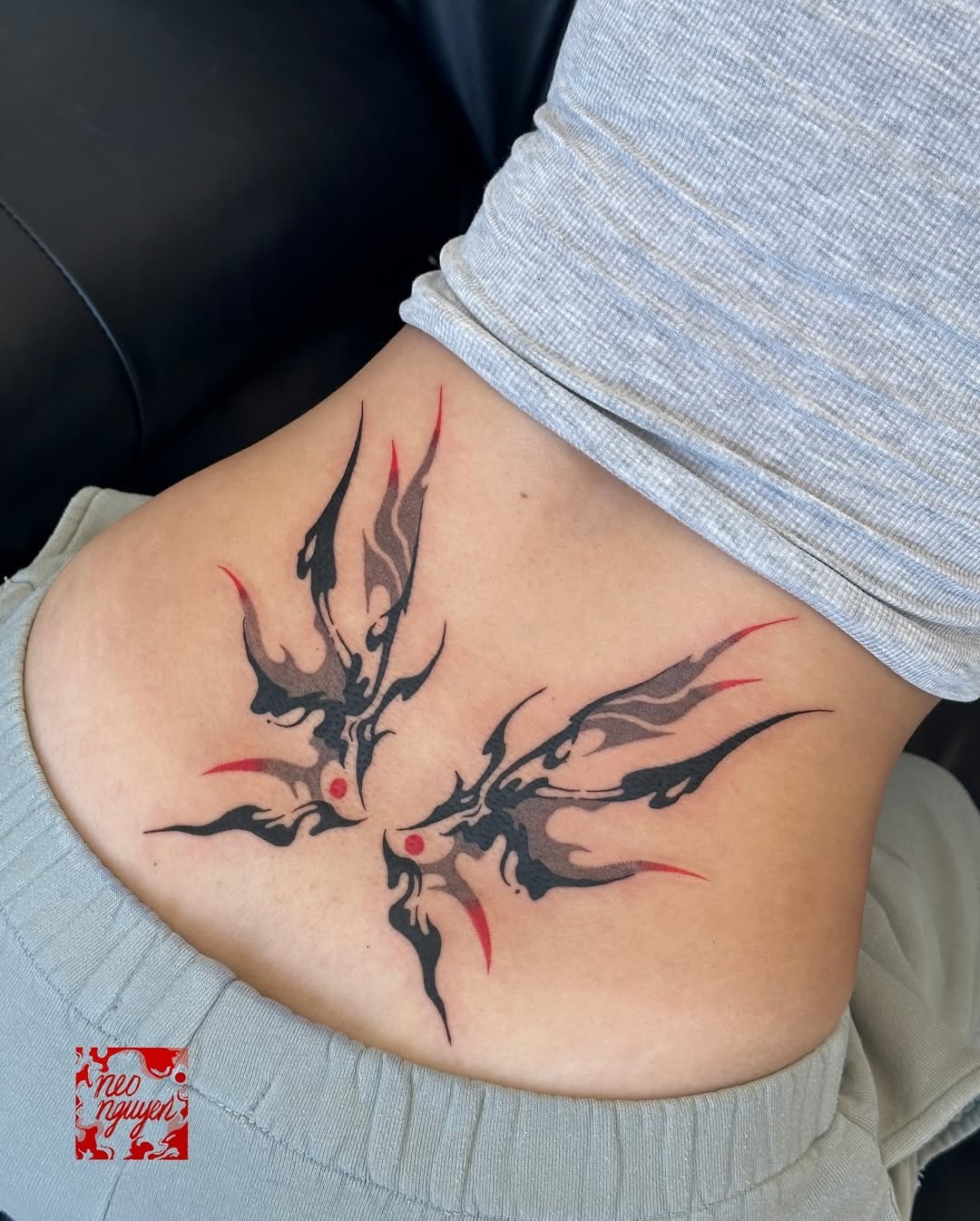 This lower back tattoo features a unique representation of flame-like butterflies, intertwining elegance with an edgy vibe.