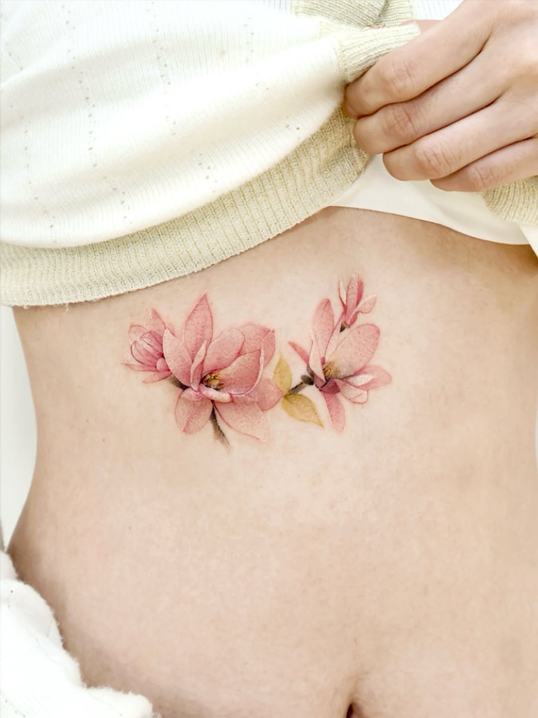 Delicate pink magnolia tattoo on the rib Tattoo Design