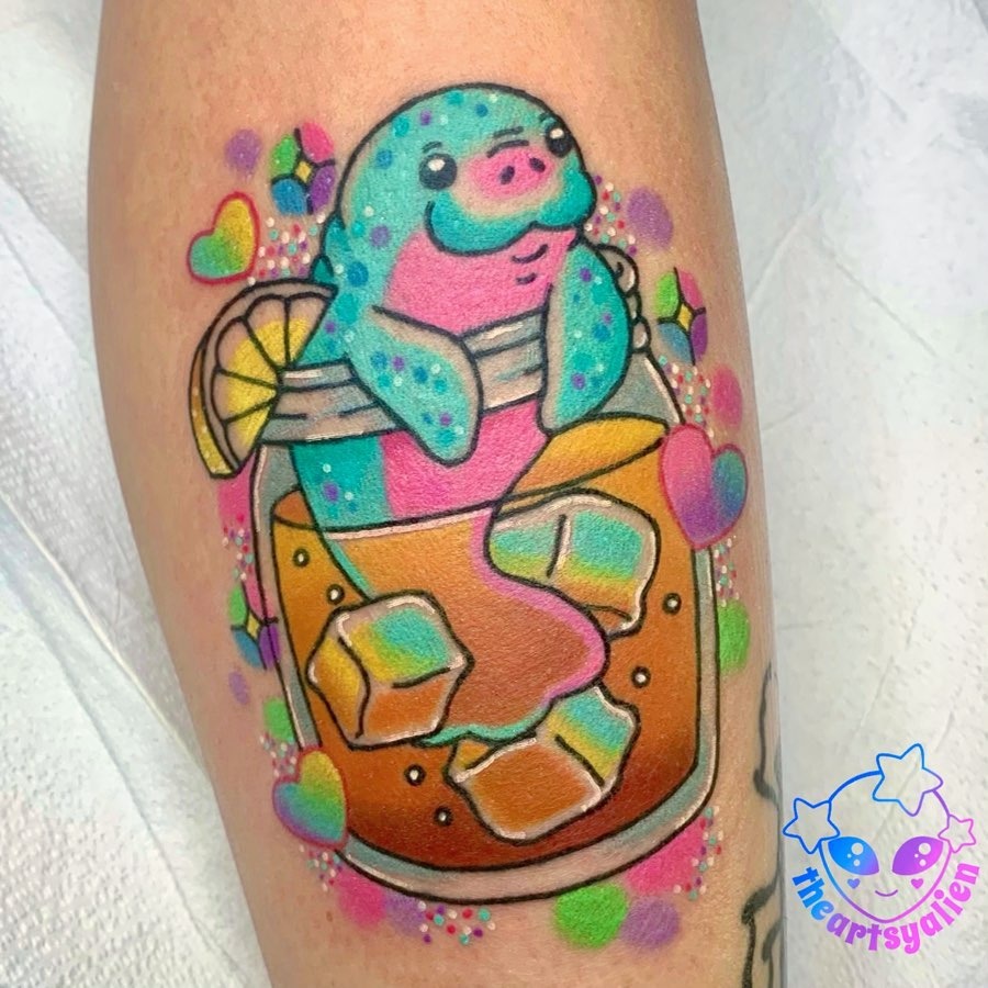 This tattoo features a cheerful manatee lounging in a cocktail glass.