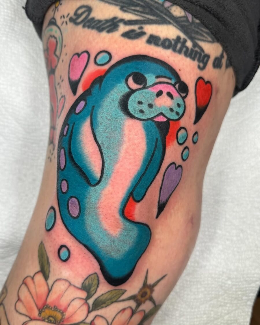 This manatee tattoo features bright blue tones and playful bubbles.