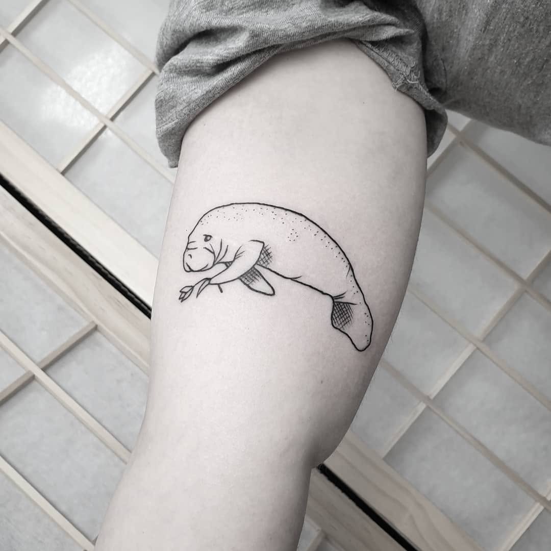 This playful manatee tattoo showcases a sleek, minimalist design that adds a unique touch to the thigh.