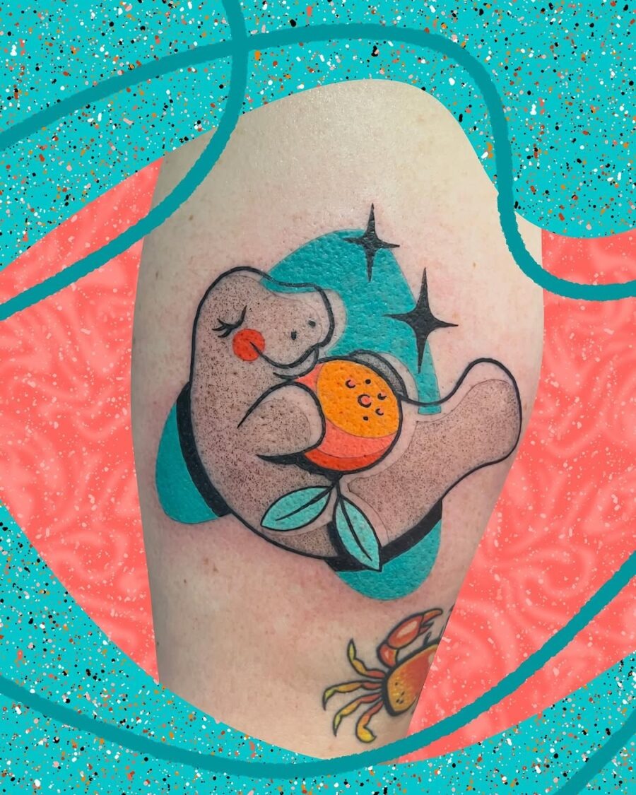 This tattoo features an adorable manatee holding an orange, radiating joy and whimsy.