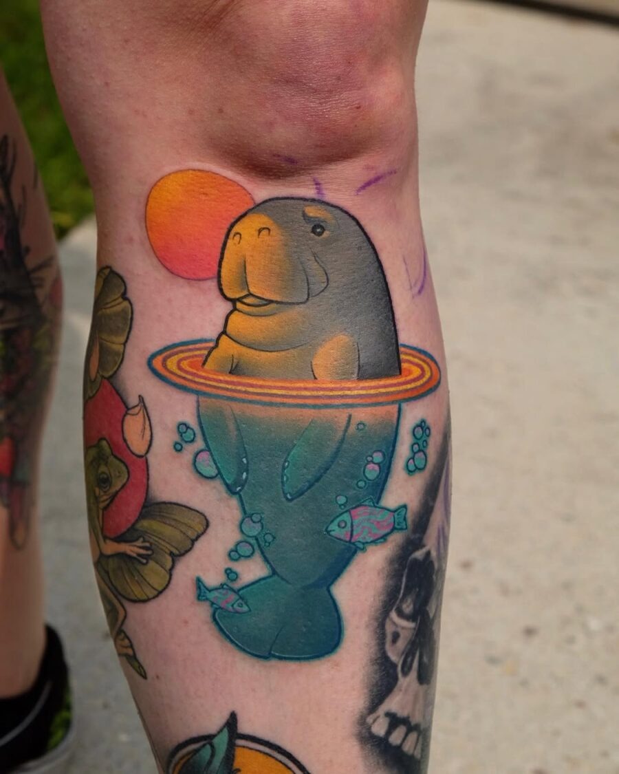 This tattoo features a whimsical manatee surrounded by colorful bubbles and a brilliant sun.