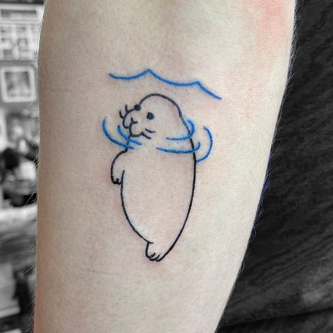 This tattoo features a cute manatee surrounded by gentle waves in a minimalist style.