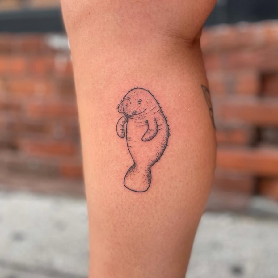 This delightful tattoo depicts a friendly manatee in a minimalist black outline.