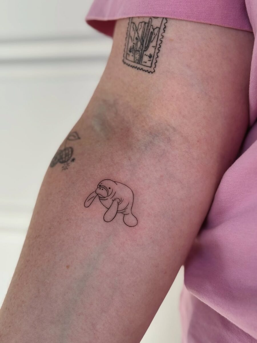 This delightful tattoo features a small, simplistic manatee design.