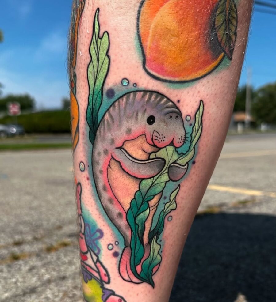 This playful manatee tattoo features bright colors and detailed seaweed, bringing a joyful vibe to the wearer.