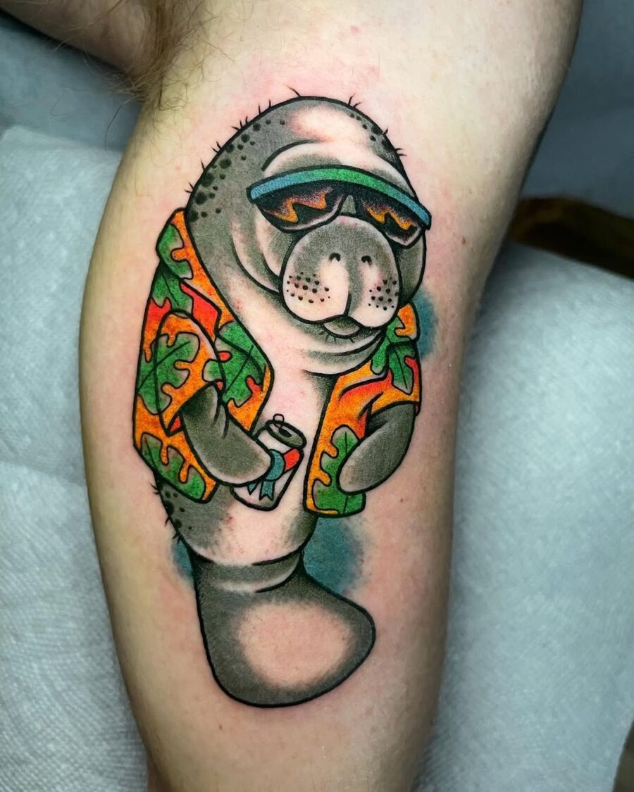 This tattoo features a cheerful manatee dressed in a, tropical shirt and sunglasses, holding a drink.