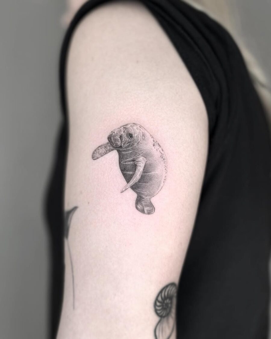 This stunning tattoo showcases a beautifully detailed manatee, perfectly placed on the arm.