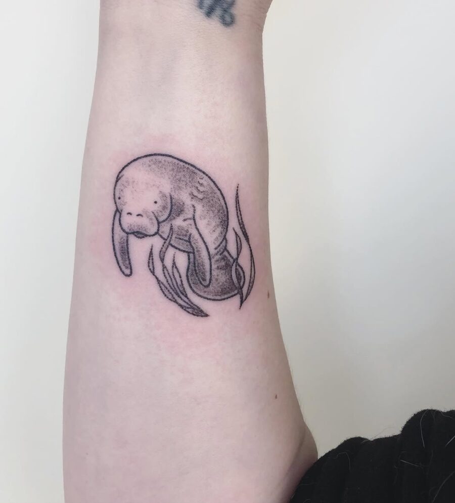 This tattoo features a delicate representation of a manatee in black ink.