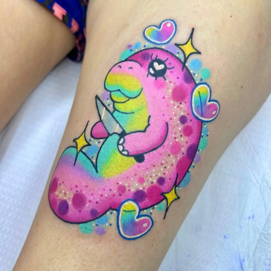 This tattoo features a colorful, cartoonish manatee holding a knife, complete with charming heart accents.