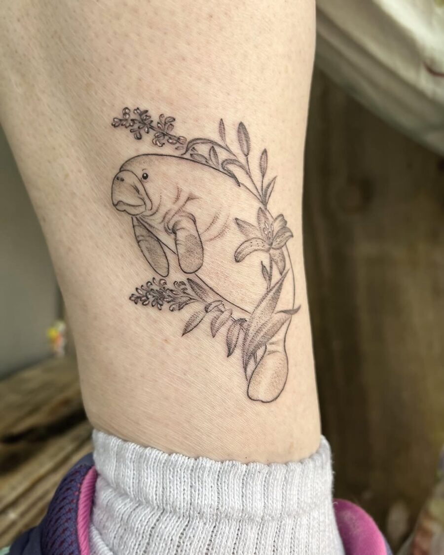 This charming tattoo features a manatee entwined in delicate flowers, showing an artistic flair.