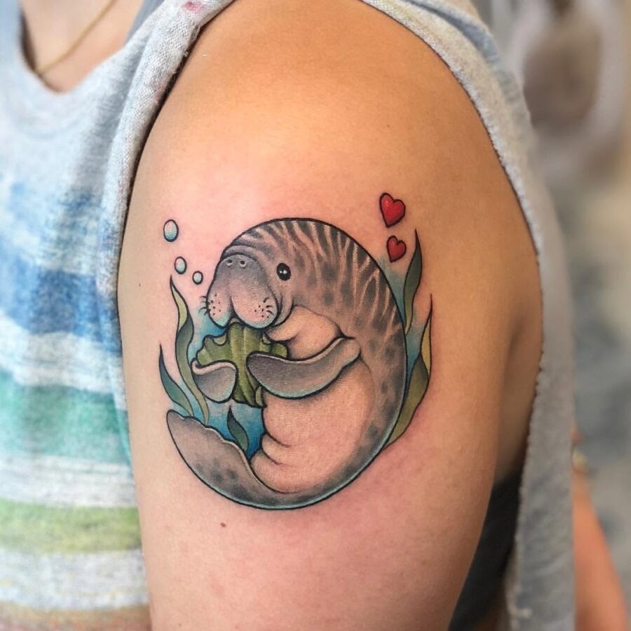 This tattoo showcases a whimsical manatee gently holding sea grass.