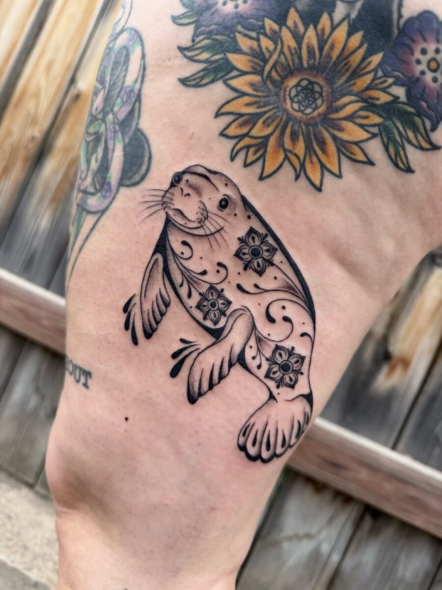 This tattoo showcases a delightful manatee adorned with intricate floral motifs.
