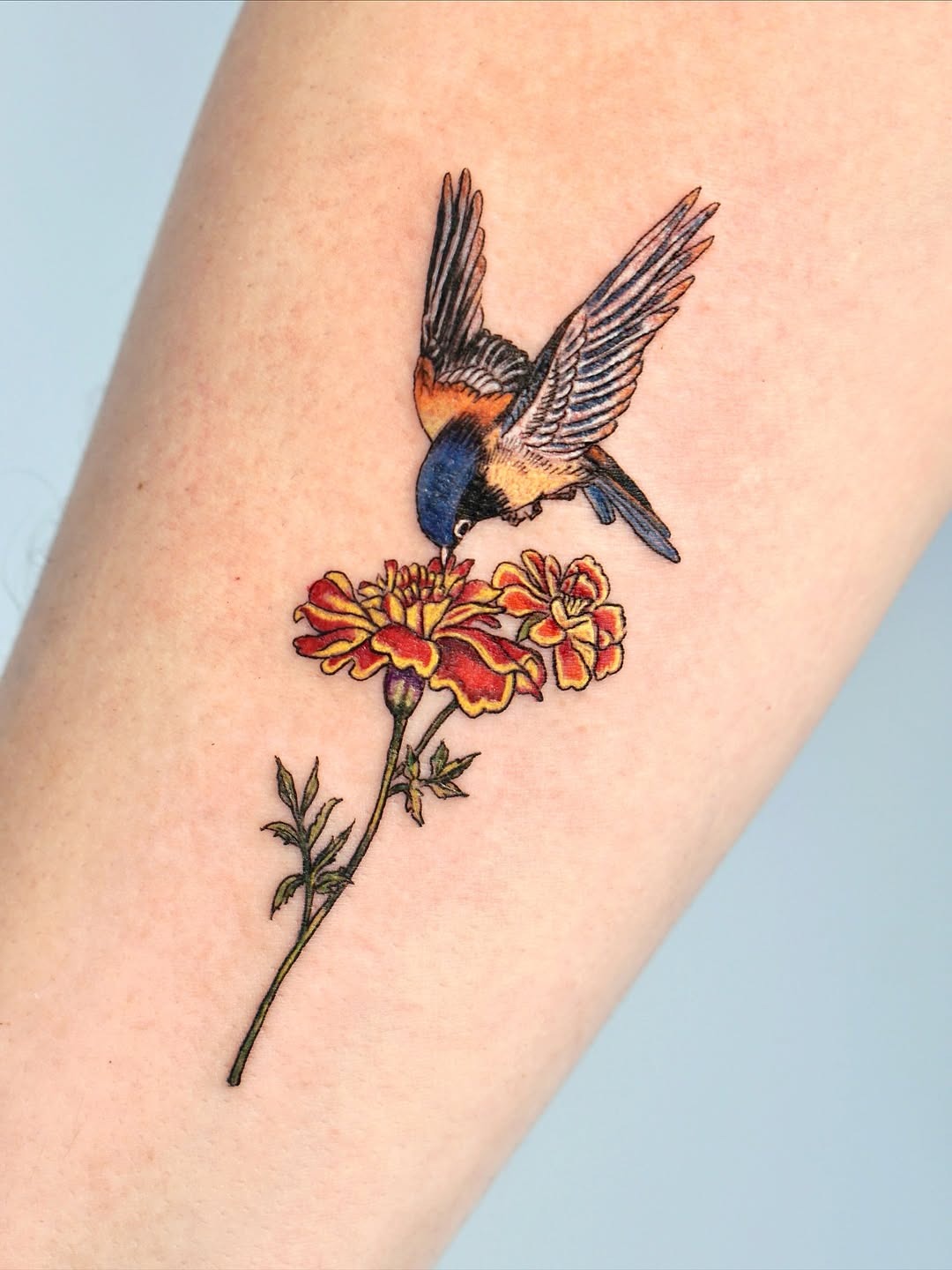 Charming marigold tattoo with vibrant bird detail Tattoo Design