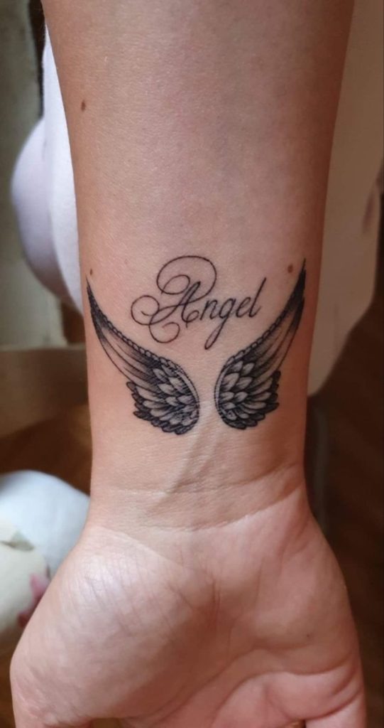 This tiny and dainty tattoo features a minimalist set of wings paired with the word "Angel" in graceful script.