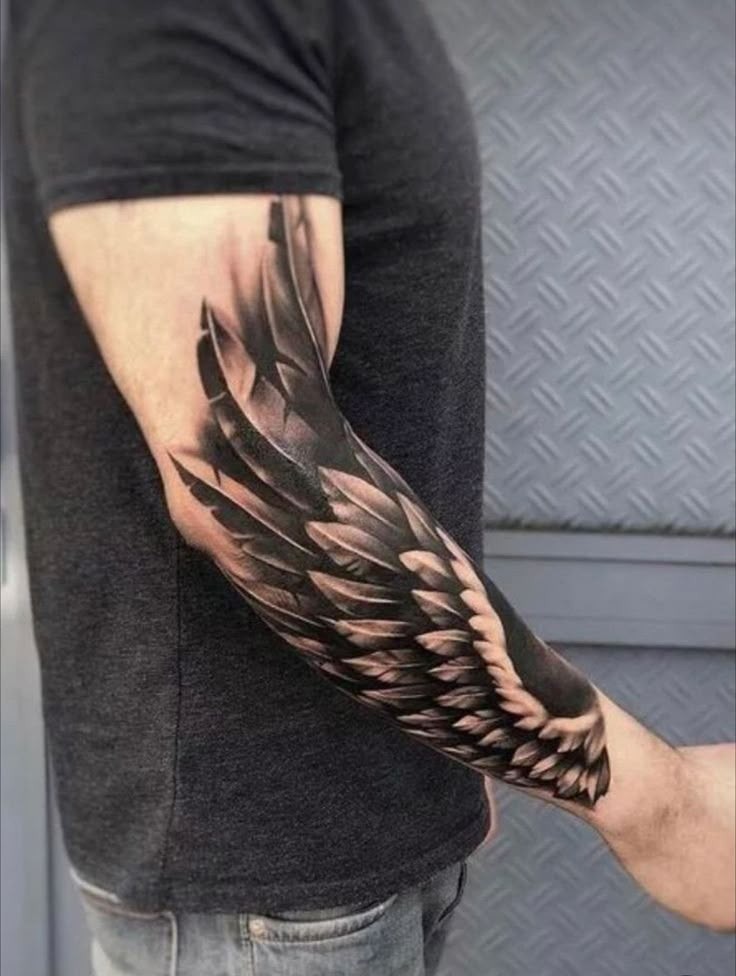 This dramatic forearm and arm tattoo plays with high contrast, deep blacks, and feather highlights to create a wing that seems to flicker in motion.