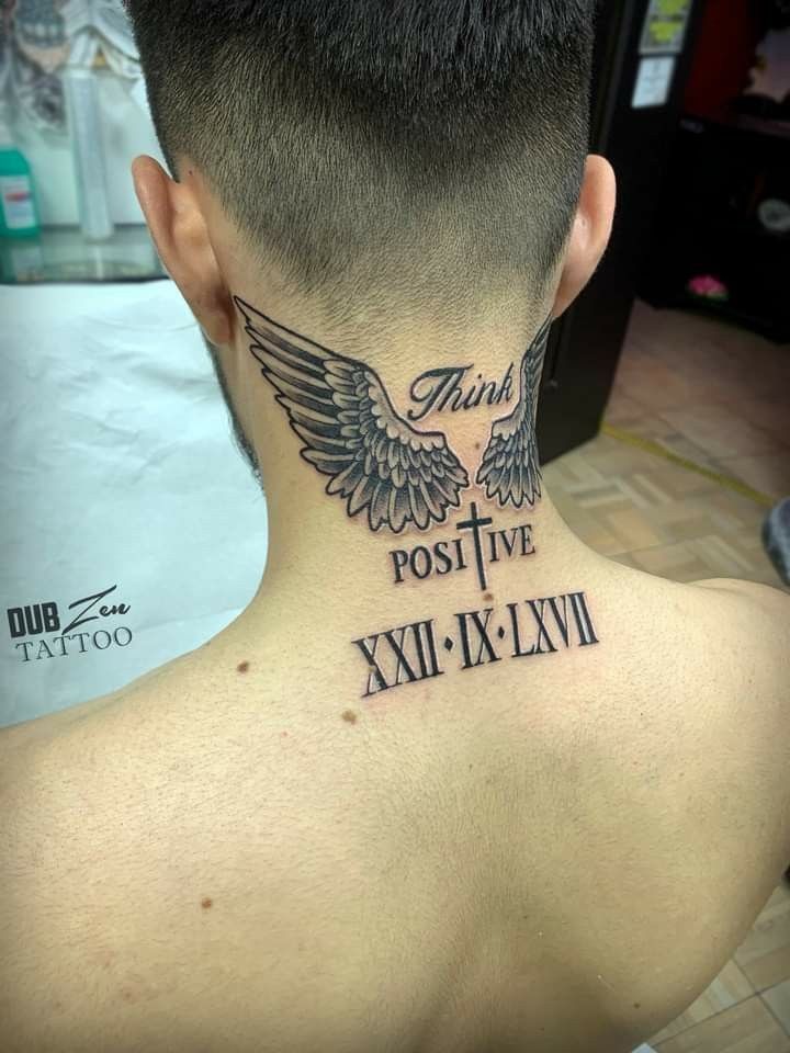 A stylish and uplifting neck tattoo that integrates feathered wings, a cross with vertical placement, and motivational script.