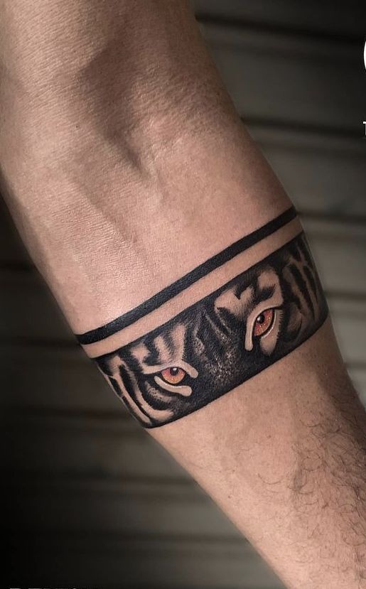 Few tattoos command attention like this one: a striking tiger's gaze wrapped around the arm in a smooth band, with lifelike eyes rendered in vivid color.