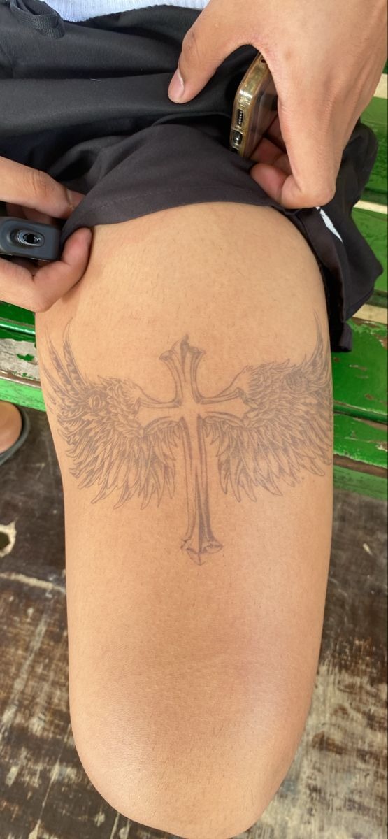 Cross With Winged Shield, a tattoo design rendered in clean detailed linework for the thigh.