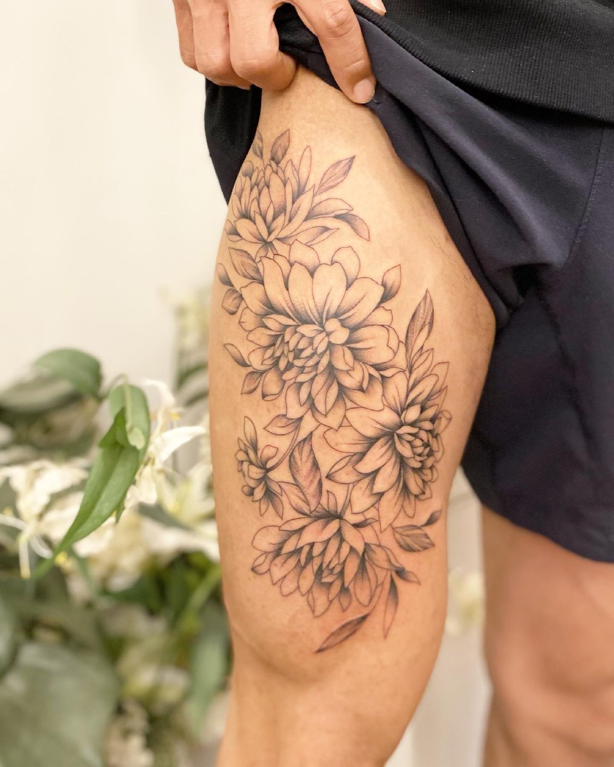 Floral Elegance Thigh Tattoo, a tattoo design rendered in delicate fine-line.