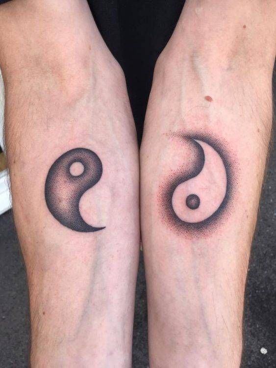 Two opposite forearms display a remarkable matching pair of Yin Yang symbols in this remarkable twin tattoo.