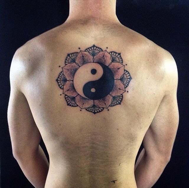 Combining sacred geometry with Eastern philosophy, this back tattoo places a yin-yang emblem over delicate lotus petal patterns.