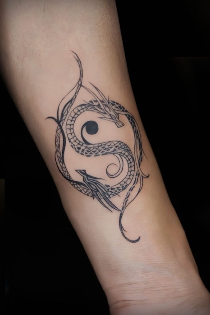 The illustration shows two stylized dragons coiled tightly together with their bodies forming the traditional yin-yang pattern.