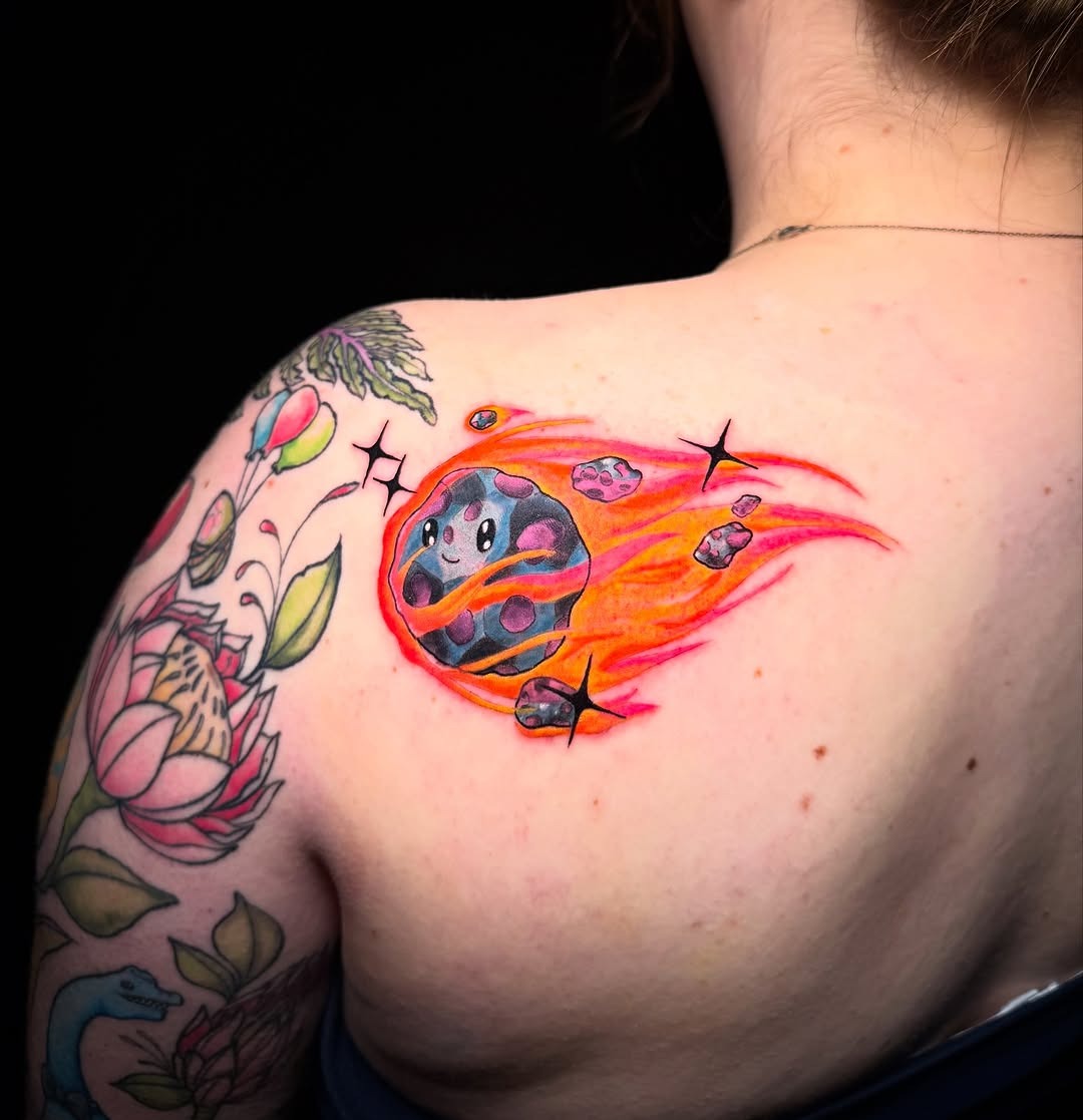 This meteor tattoo features a cartoonish planet surrounded by fiery trails and stars.