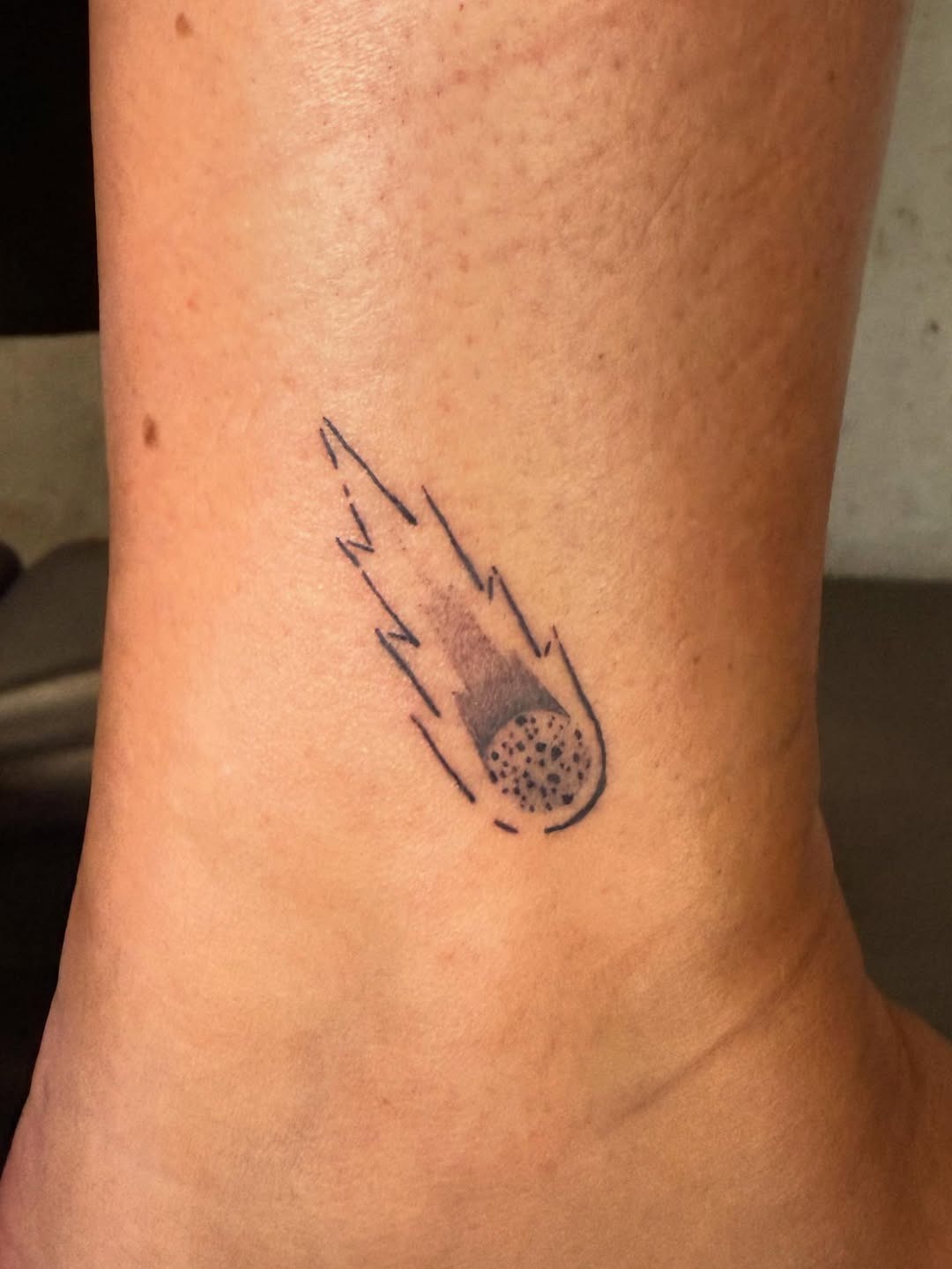 This meteor tattoo is small yet dynamic, featuring a streak of movement that captures the essence of a shooting star.