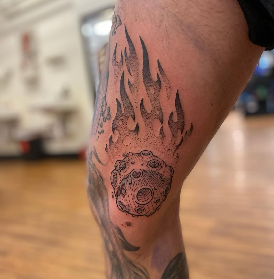 This striking tattoo captures a meteor soaring upward, enveloped by stylized flames.