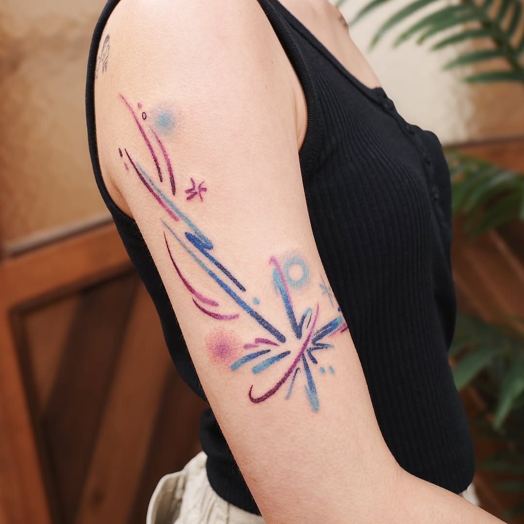 This tattoo showcases a meteoric explosion with lively lines and splashes of color.