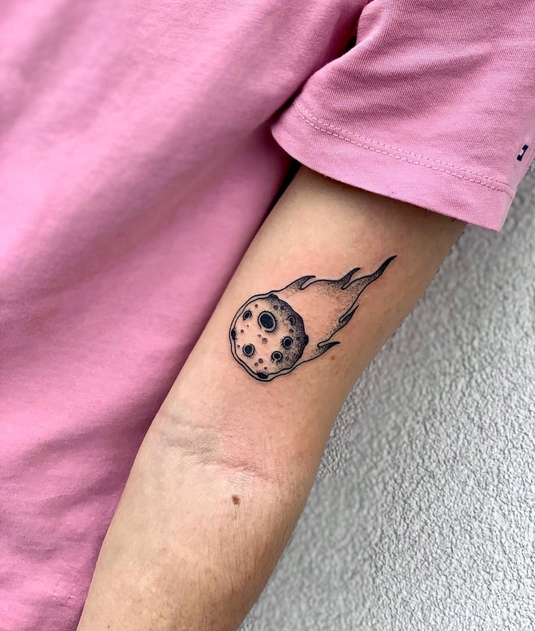 This tattoo features a detailed meteor with swirling flames, creating an energetic and eye-catching design.