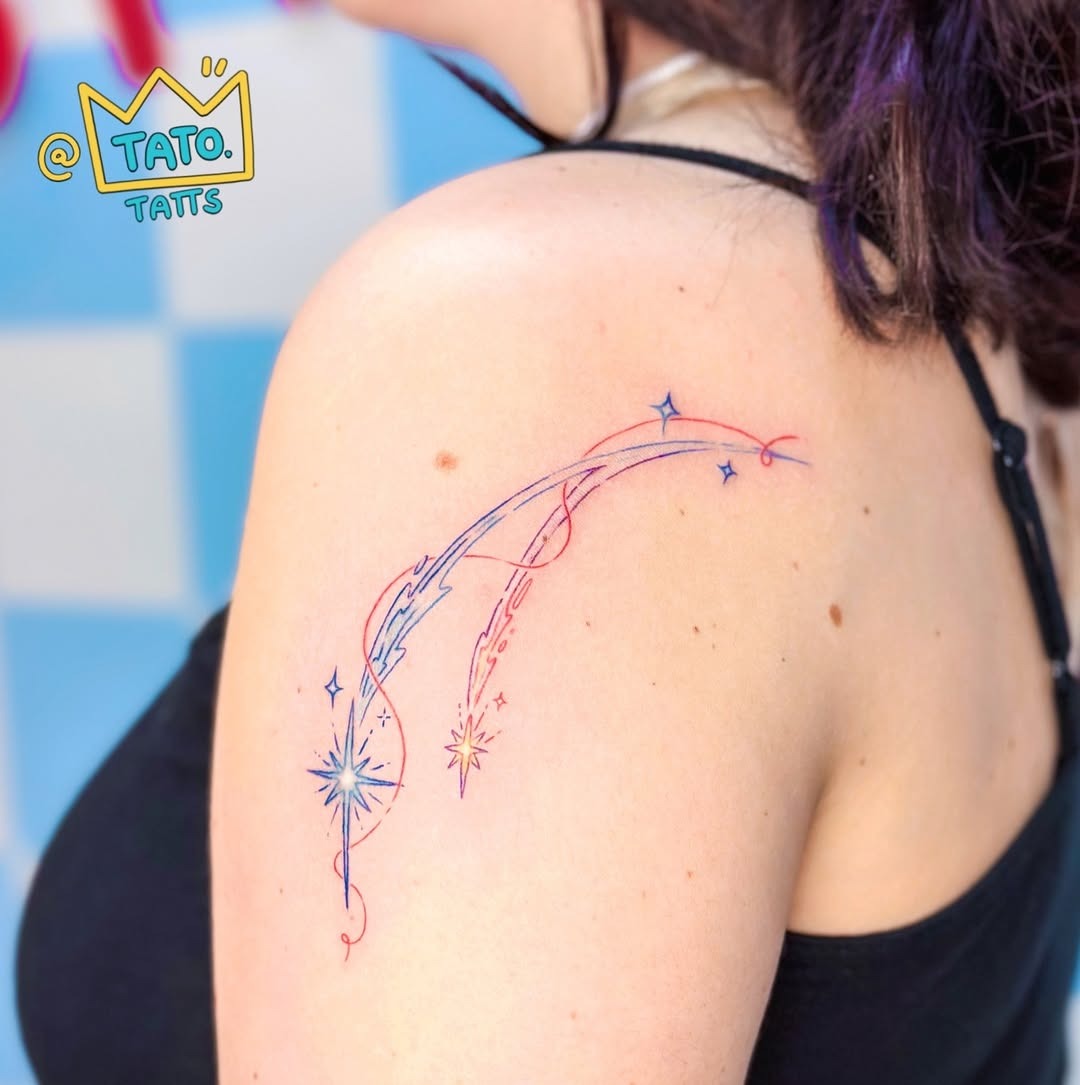This tattoo features a graceful meteor streaking across the skin, highlighted by delicate swirls and sparkling stars.