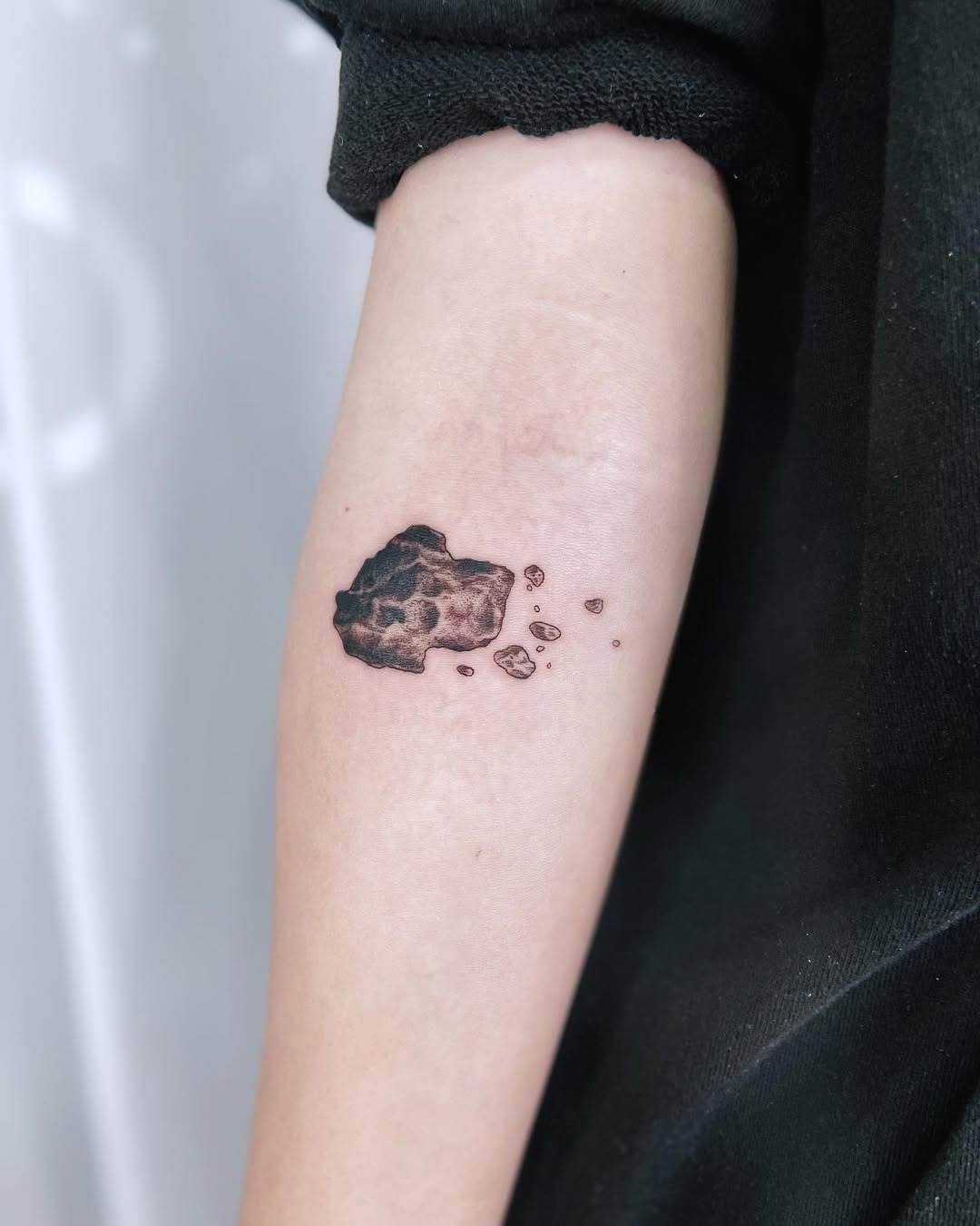 This meteor tattoo displays a detailed depiction of a celestial body, complete with surrounding debris.